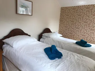two beds in a room with blue towels on them at High House Cottage - A traditional home from home in St Bees