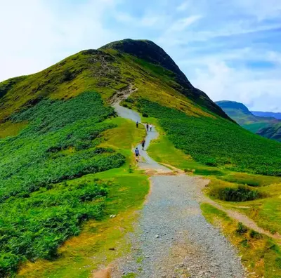 a mountain with people walking down a trail at Catbells Sunrise Cottage Borrowdale Lake District in Keswick