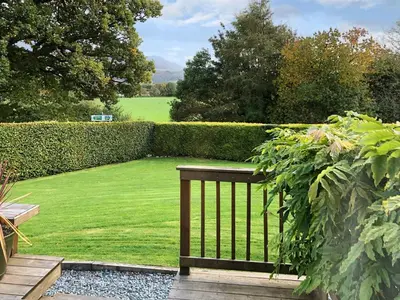 a garden with a bench and a hedge at Autumn Leaves in Keswick