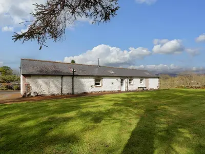 a white building with a grass field in front of it at The Stables in Thornhill