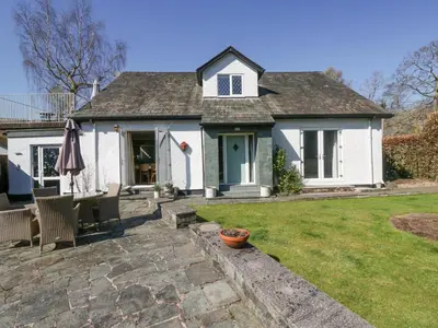 a white house with a table and chairs in a yard at Osprey Cottage in Ambleside