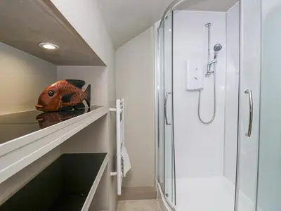 a bathroom with a walk in shower and a glass door at Osprey Cottage in Ambleside