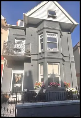 a large gray house with windows and a balcony at Coastal Cwtch in Moffat