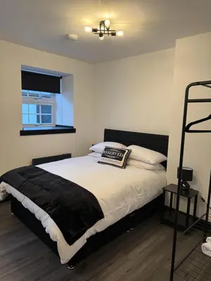 a bedroom with a bed with a black blanket at GlasVenn Cottages in Irvine