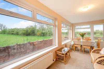 a dining room with large windows and a table and chairs at 3 Bed in Aspatria oc-w31951 in Hayton