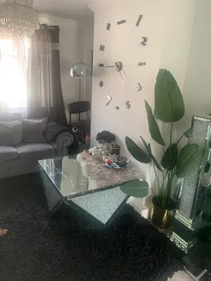 a living room with a glass table and a clock on the wall at Dmoney Ltd in Moffat