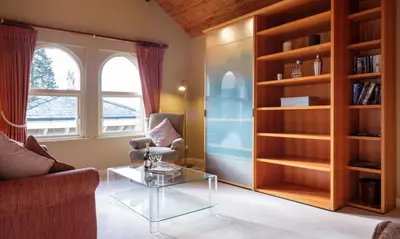 a living room with a glass table and a book shelf at Robinson in Keswick