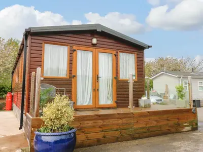 a small wooden cabin with a large wooden deck at Cates Cozy Cabin in Carlisle
