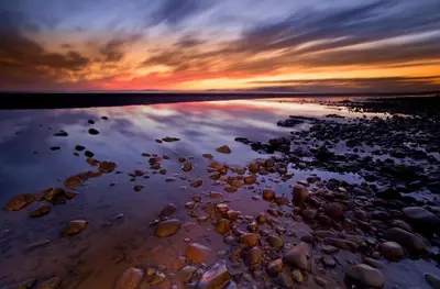 a sunset over a beach with rocks in the water at 2 Bed in Allonby oc-i30743 in Allonby