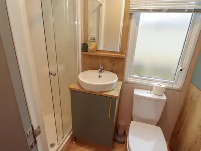 a bathroom with a toilet and a sink and a window at Seren in Cockermouth
