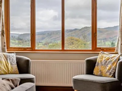 a room with two chairs and a window with mountains at 3 Bed in Keswick oc-93590 in Threlkeld