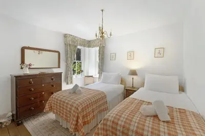 a bedroom with two beds and a dresser and a mirror at Poet's View Cottage in Grasmere