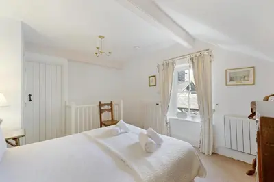 a white bedroom with a bed and a window at Poet's View Cottage in Grasmere