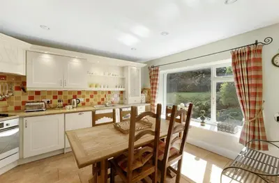 a kitchen with a wooden table and a dining room at Poet's View Cottage in Grasmere