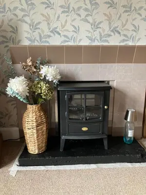a black stove with a vase of flowers in a room at Wee Lyon Cottage Maybole 2 Bedroom Sleeps 4 in Maybole
