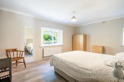 a bedroom with a bed and a chair and a window at The Stables Cottage, Beattock, Moffat in Beattock