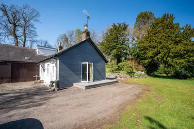 a small blue building with a door in a yard at The Stables Cottage, Beattock, Moffat in Beattock