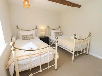 two twin beds in a bedroom with white walls at Corner Cottage in Penrith