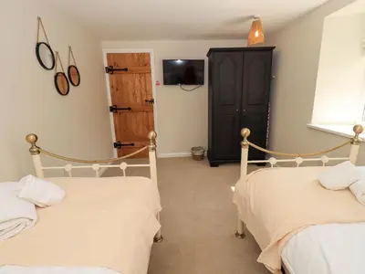 two beds in a room with a tv on the wall at Corner Cottage in Penrith