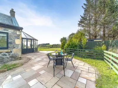 a patio with a table and chairs next to a building at Torr Cottage in Dalrymple