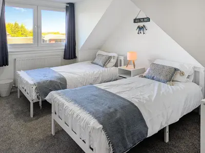 a bedroom with two beds and a window at Torr Cottage in Dalrymple