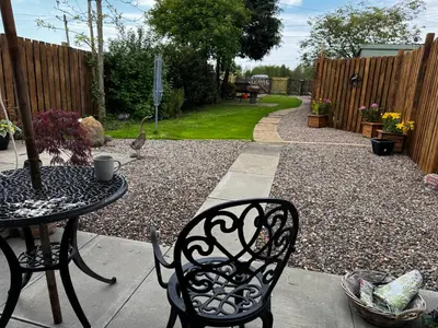 a patio with a table and chairs and a fence at Cosy Wee Cottage in Monkton