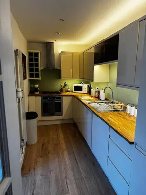 a kitchen with blue cabinets and a wooden counter top at Cosy Wee Cottage in Monkton