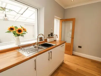 a kitchen with a sink and a window with a vase of sunflowers at Grace House in Wigton