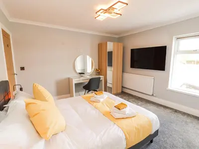 a bedroom with a large bed with a tv on the wall at Grace House in Wigton