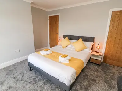 a bedroom with a large bed with two towels at Grace House in Wigton