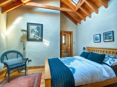 a bedroom with a large bed and a chair at Lighthouse Studio Apartment in Portpatrick
