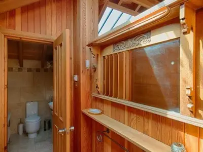 a wooden bathroom with a toilet and a window at Lighthouse Studio Apartment in Portpatrick