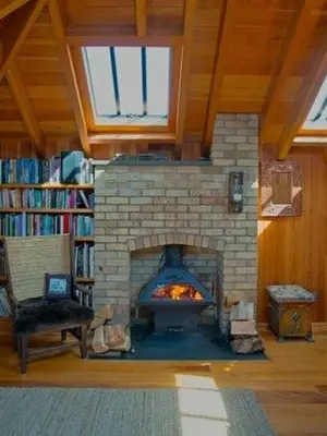 a living room with a brick fireplace in a library at Lighthouse Studio Apartment in Portpatrick