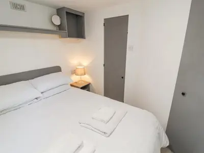 a bedroom with a white bed with two white towels at No 29 Wyndham Hall in Cockermouth