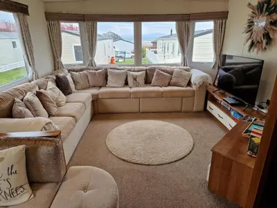 a living room with a couch and a television at Peaceful Seaside Getaway in Mainsriddle