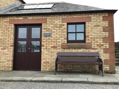 a brick building with a bench in front of it at Lightkeepers Snug in Portpatrick