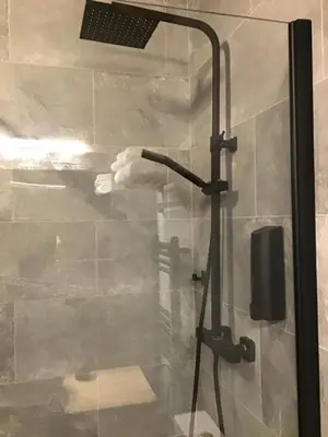 a glass shower with a hand holding a shower head at Lightkeepers Snug in Portpatrick