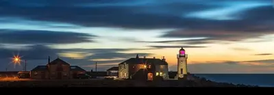 a light house with a lighthouse on the beach at Lightkeepers Snug in Portpatrick