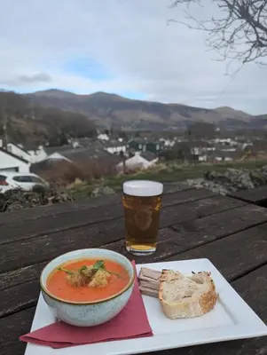 a bowl of soup and a glass of beer on a table at Zions Retreat in Plumbland