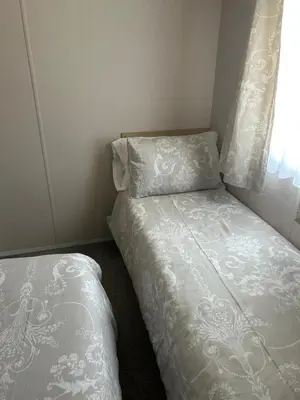 a small bedroom with two beds and a window at One Muirfield, Caravan at Turnberry in Turnberry