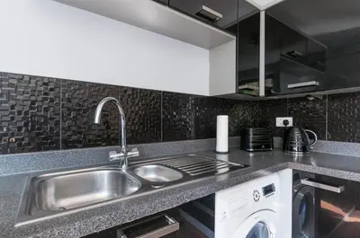 a kitchen with a sink and a washing machine at The Cozy Atmosphere Lodge in Moffat