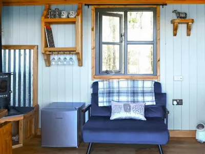 a blue chair in a room with a window at The Shepherd's Rest in Auchencairn