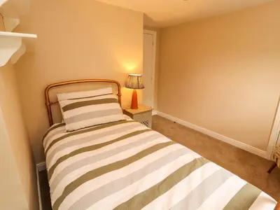a small bedroom with a bed and a lamp at Kirkland Howe Cottage in Frizington