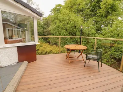 a wooden deck with a table and a chair at Kirkland Howe Cottage in Frizington