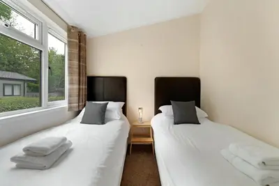 two beds in a room with a window at Troutbeck Lodge in Bassenthwaite