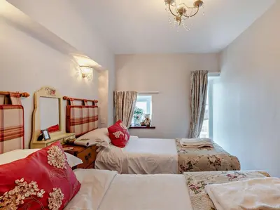 a bedroom with two beds and a mirror and a chandelier at 2 Bed in Ireby 96088 in Ireby