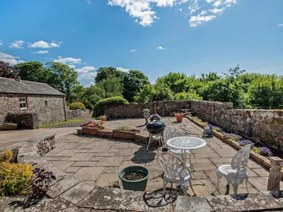a patio with a table and chairs and a stone wall at 2 Bed in Ireby 96088 in Ireby
