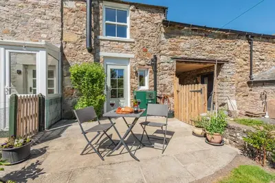 a patio with a table and chairs in front of a building at 2 Bed in Caldbeck oc-a32049 in Caldbeck