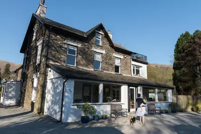 a man and a woman and a dog in front of a house at Lake View Country House and Self-catering Apartments in Grasmere