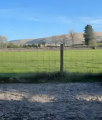 a fence in the middle of a field at Cozy Cottage in Caldbeck in Caldbeck
